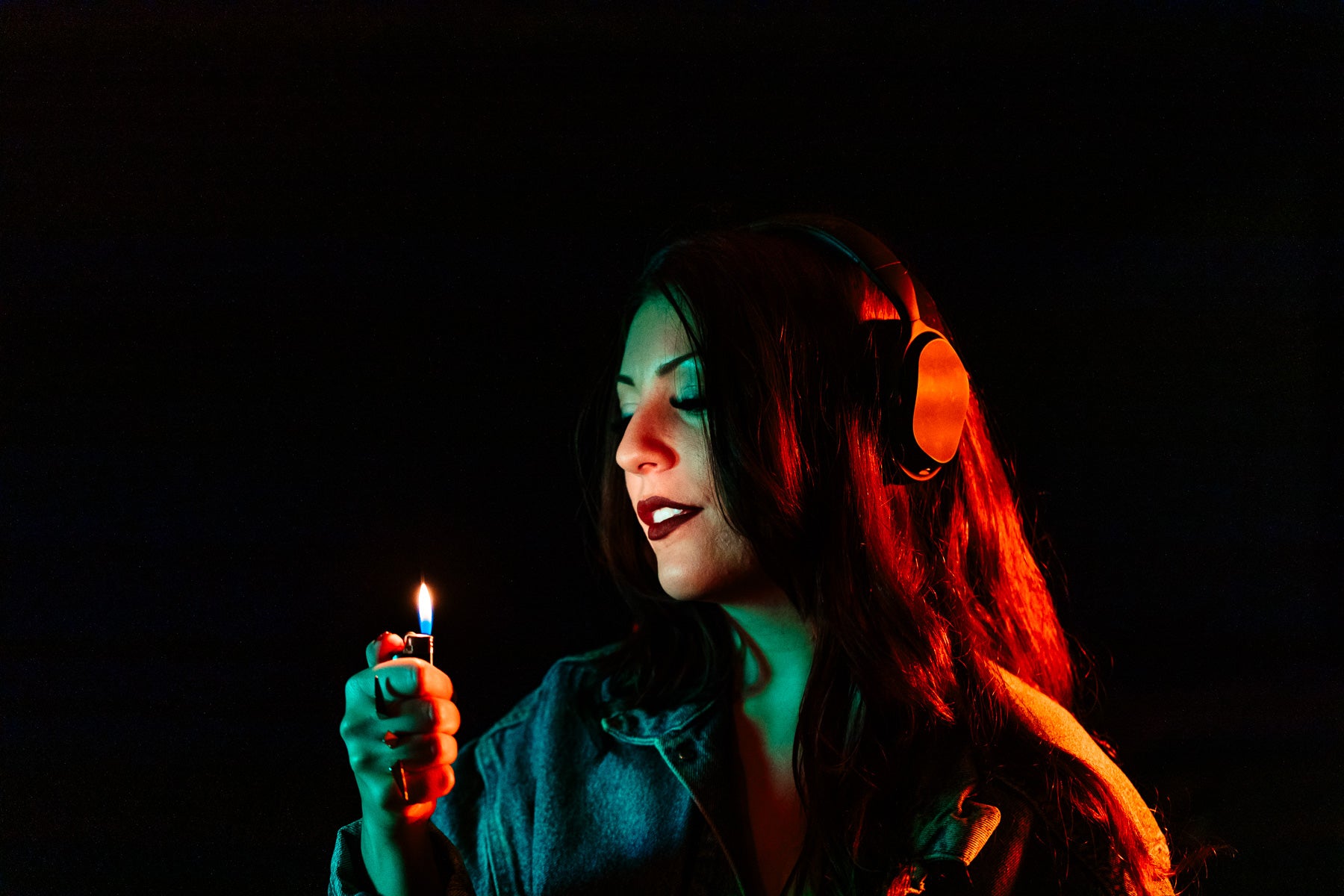woman with dark lipstick stares at lit lighter as the light reflects on her face
