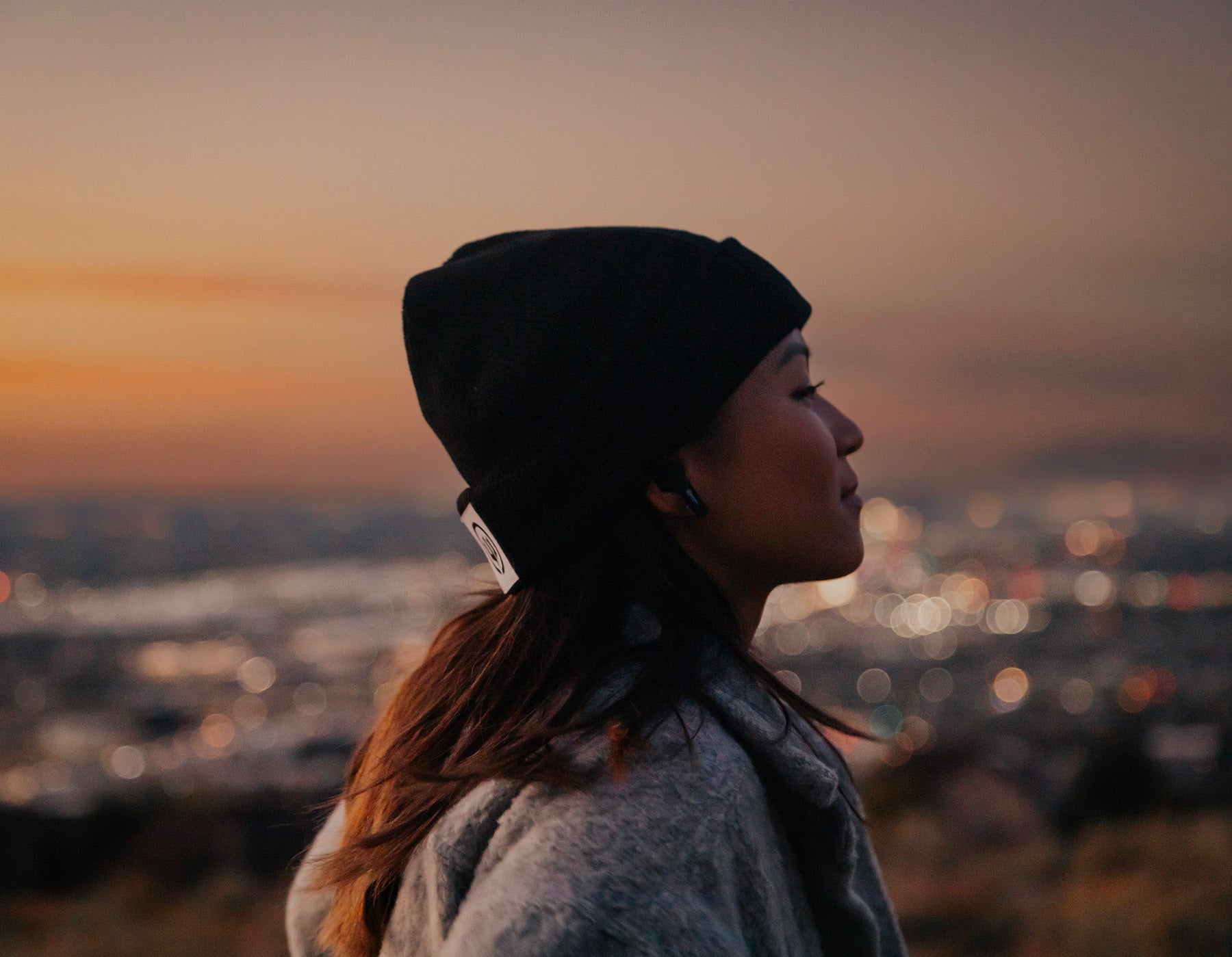 woman an sunset smiles while wearing earbud