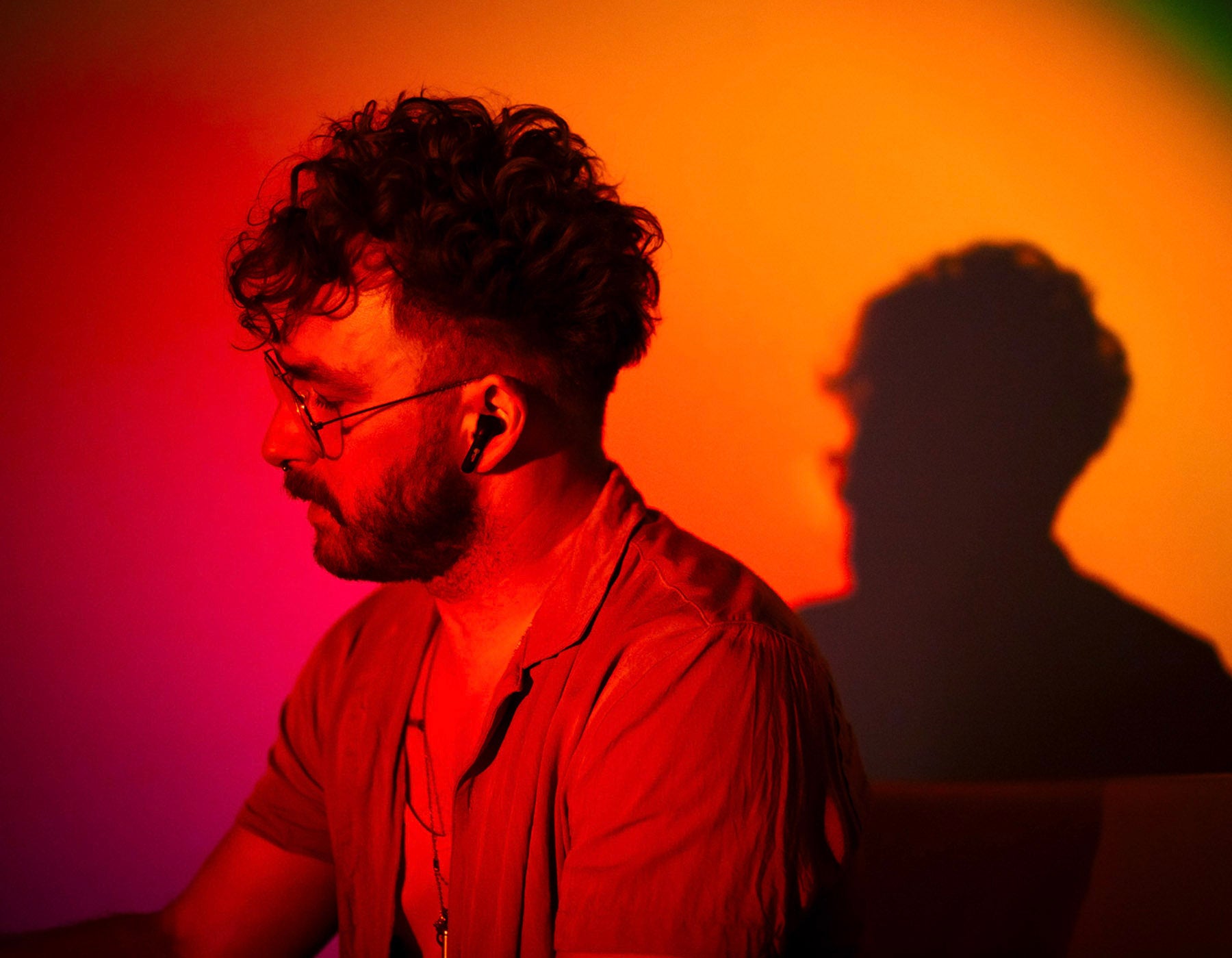 an orange light illuminates a man wearing earbuds