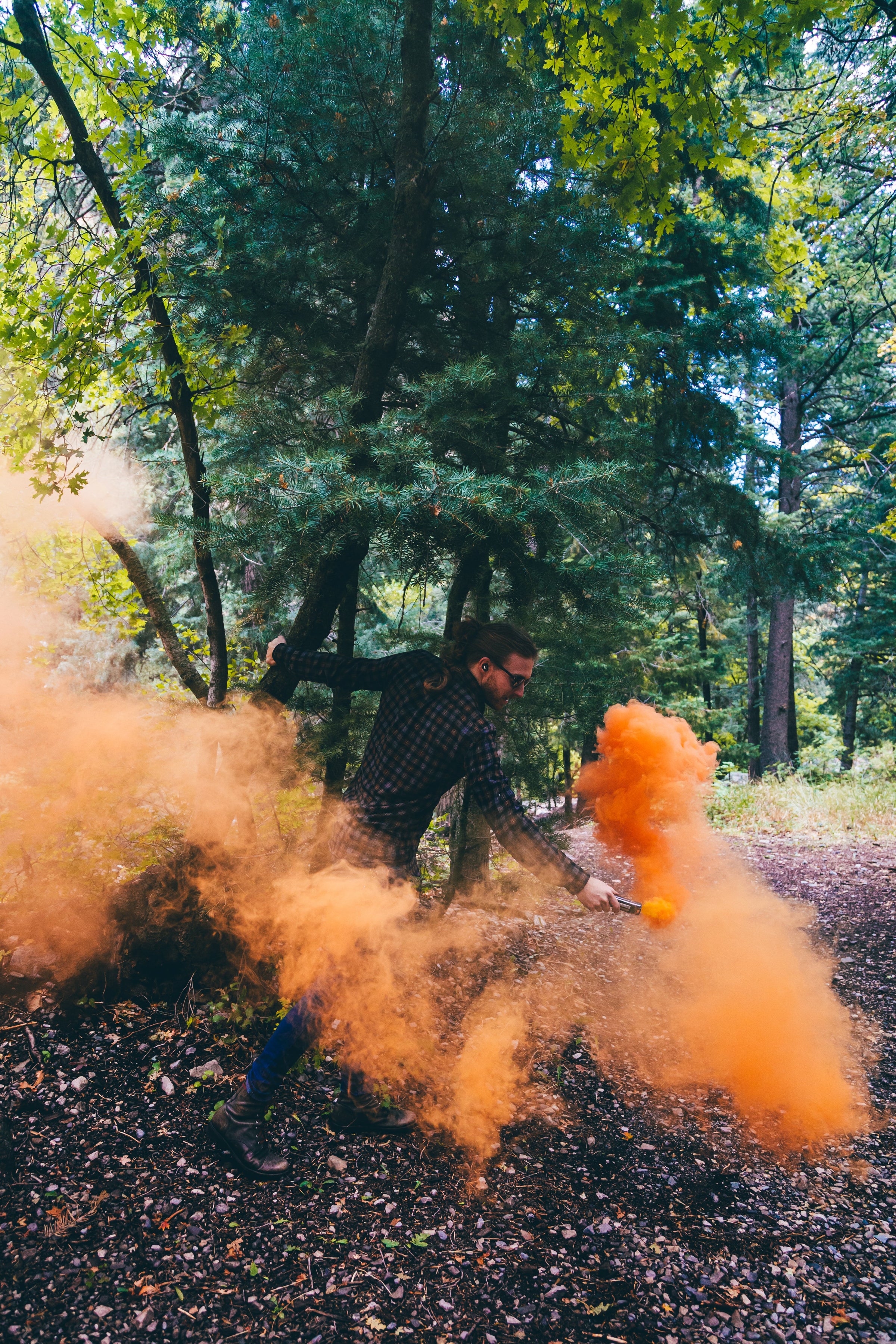 Man using orange smoke bomb in the woods.