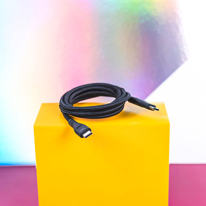 Black charging cable sitting coiled on yellow box