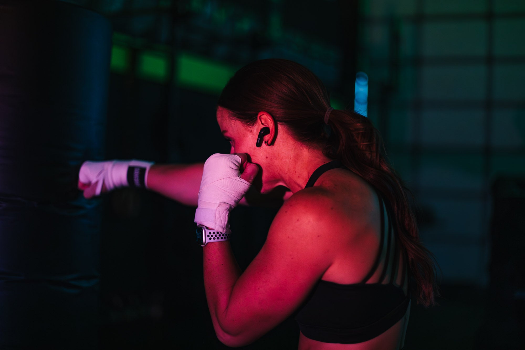 Woman wearing earbud while kickboxing
