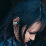 Woman with black hair looking down wearing  Drive 600cc Wired Earbud