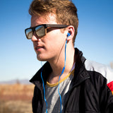 Male model with sunglasses wearing blue Drive 750cc Wired Earbud.