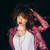 Lifestyle image of model wearing blue Drive 900cc Wired Earbud. She is wearing red leather jacket and has amazing hair.