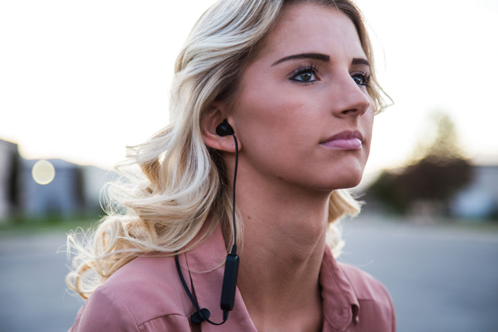 Model wearing black Omen wireless earbud